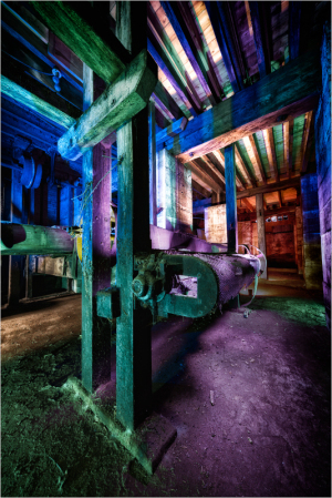 A surreal, colorful industrial scene with old machinery and beams of light.