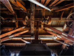 Intricate wooden beams and machinery create a rustic atmosphere overhead.