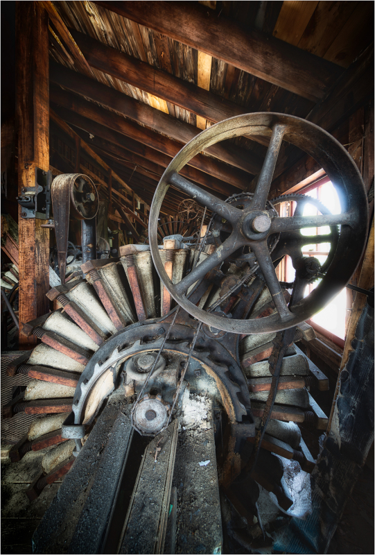 An old mill with a large, rusty wheel and wooden beams, evoking a sense of nostalgia.
