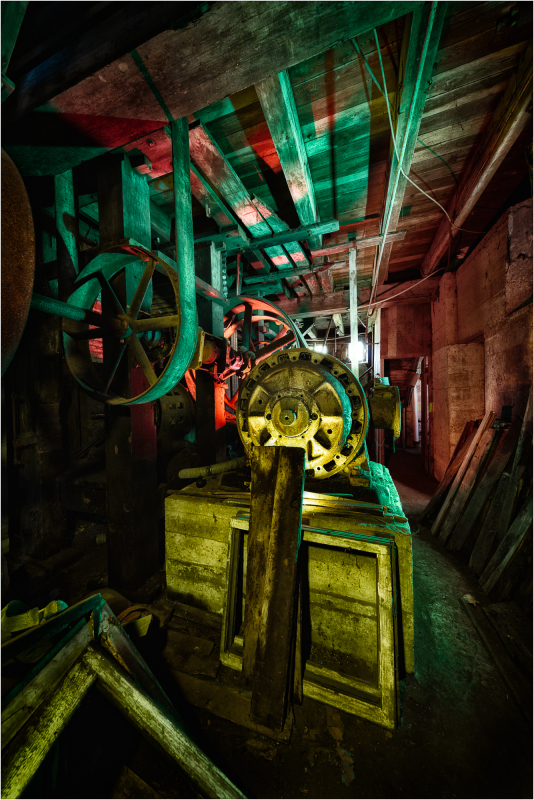 An enigmatic machine rests amidst shadows, painted in dreamlike hues of green and red.