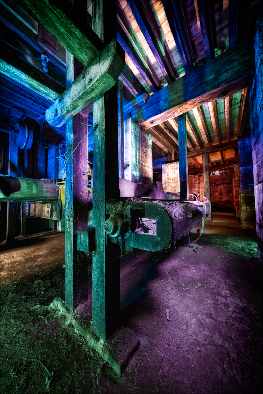 A surreal, colorful industrial scene with old machinery and beams of light.