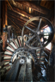 An old mill with a large, rusty wheel and wooden beams, evoking a sense of nostalgia.