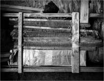 Weathered wooden shelves filled with forgotten tools and dust-covered materials.