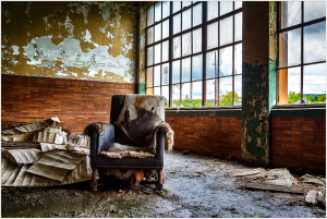 An abandoned chair amidst the remnants of forgotten times, whispers of history linger.