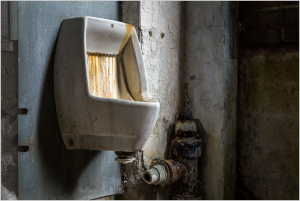 An aged porcelain urinal with rust and wear, exuding tales of time's passage.