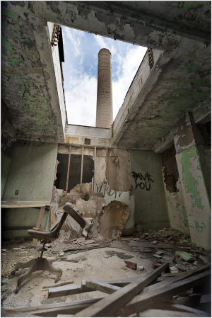A crumbling interior with a chimney peeking through the ceiling, graffiti on the walls.