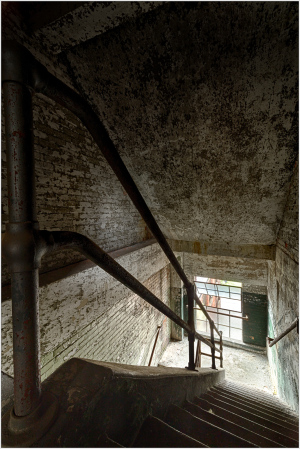 A dimly lit staircase with worn steps and peeling walls, shadows dance softly.