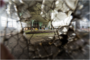 A shattered window reveals a decaying interior space filled with remnants of the past.