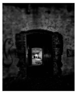 A weathered archway reveals a distant, illuminated space within crumbling walls.