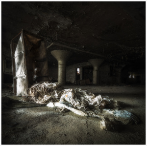 A weathered room draped in tattered fabric, shadows loom heavy.