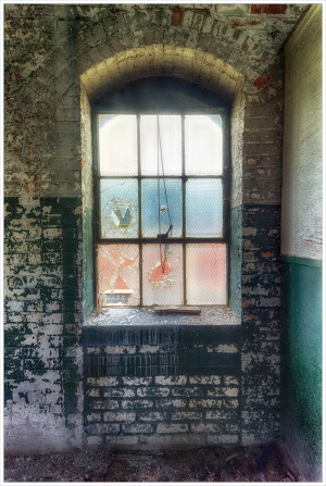 A somber window, shrouded in neglect and decay, hints at the past.