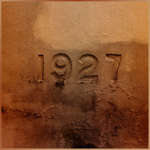 A weathered inion of the year 1927, surrounded by earthy textures.