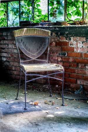 A solitary chair rests in a forgotten corner, bathed in gentle light and surrounded by nature's embrace.