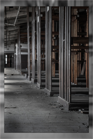 Abandoned industrial space with empty wooden frames and dust-covered floor.