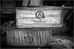 Wooden crates marked with a logo, stacked in an abandoned space.