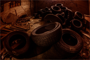 A haunting collection of aged, deflated tires amidst the shadows of neglect.