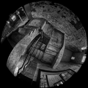 A shadowy stairwell, peeling walls, and an eerie silence envelop the scene.