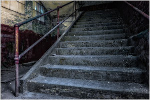 A worn staircase with peeling paint and rusting railings, echoing silence.