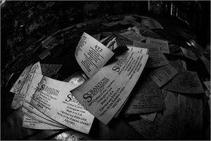 Scattered old business cards in shadow, fading memories on peeling surfaces.