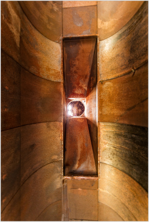 Rusty industrial funnel glowing with light, surreal ambiance.