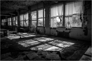 Abandoned room with torn curtains and eerie shadows dancing on the floor.