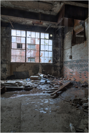Abandoned space with broken windows and debris scattered on the floor.