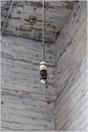 A close-up of an old light fixture hanging in a weathered wooden interior.