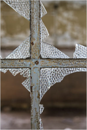 Shattered glass on rust, framing decay's silent trust.