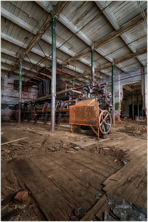 Abandoned machinery rests in a decaying industrial space, shadows dance on the weathered floor.