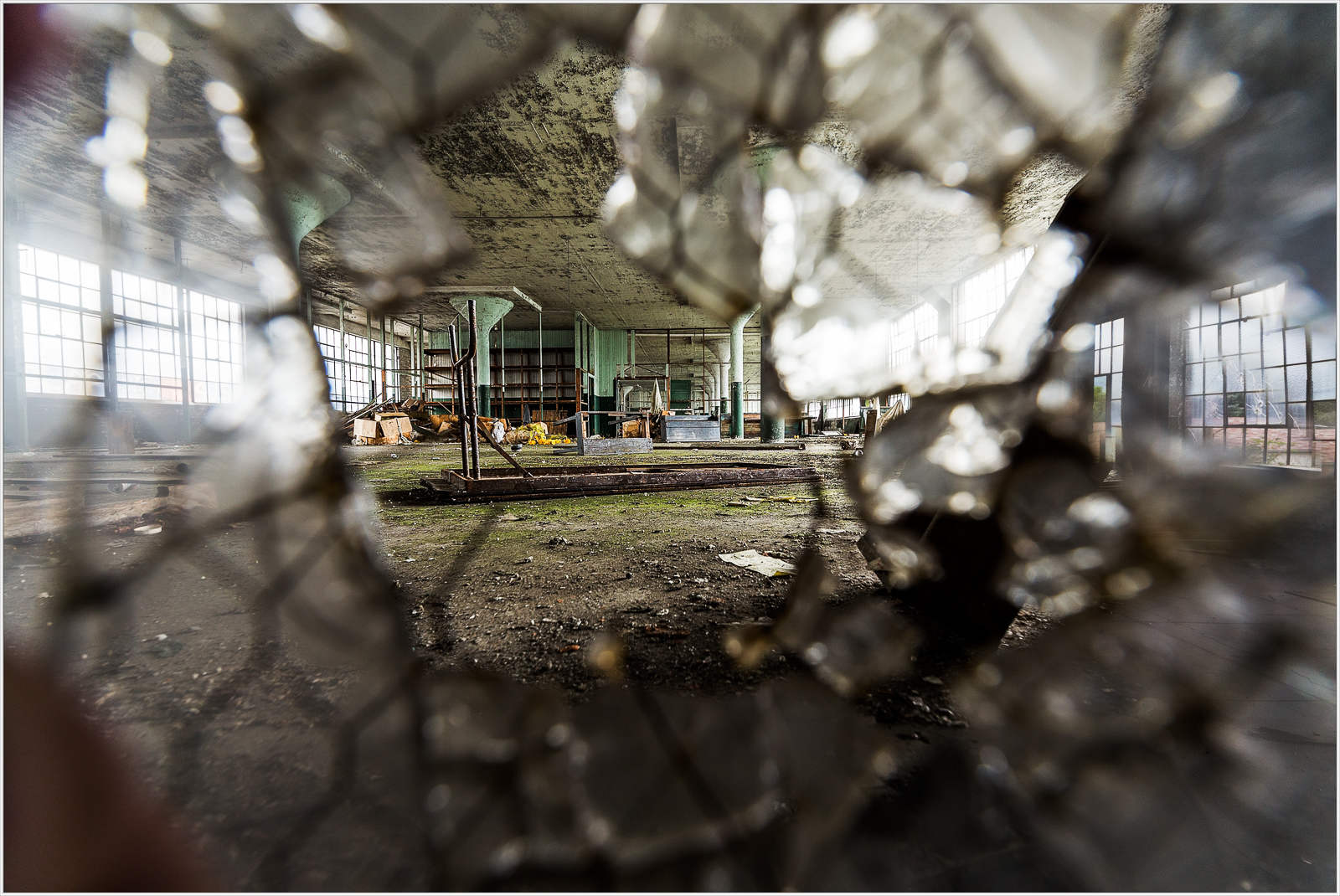 A shattered window reveals a decaying interior space filled with remnants of the past.