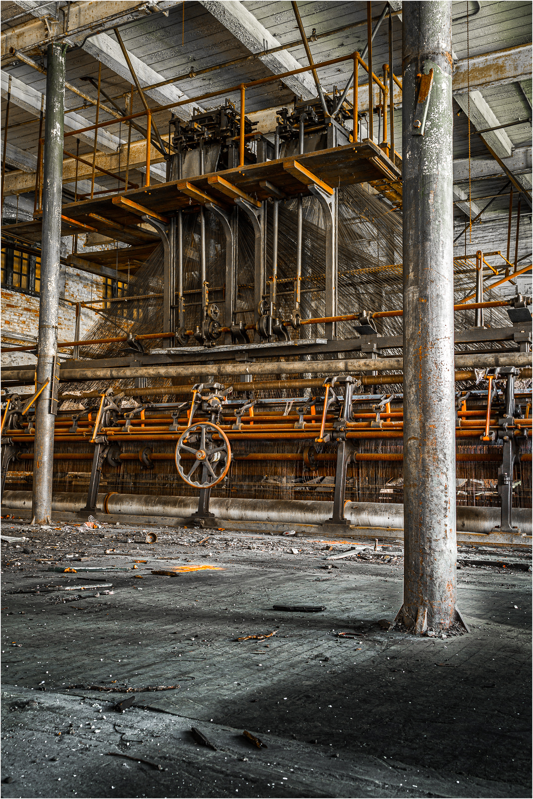 An abandoned industrial space reveals rusty machinery and a layered structure of pipes.