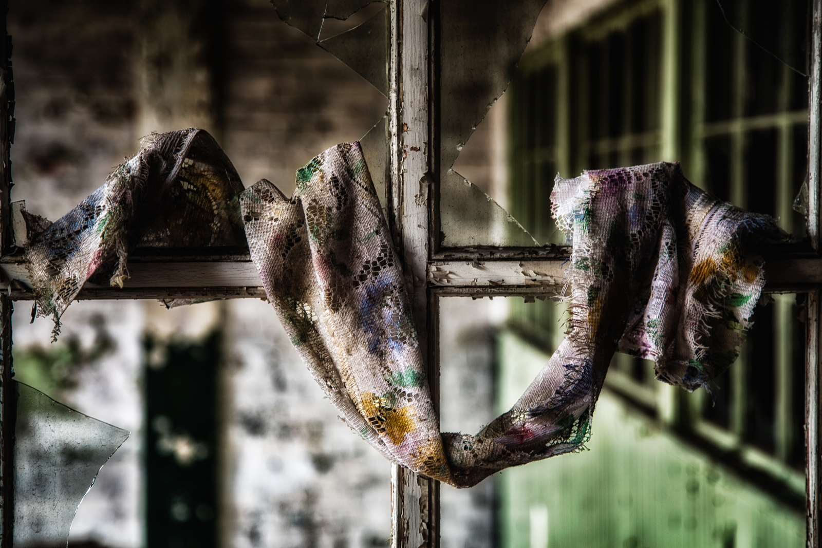 A tattered scarf draped elegantly over a rusty window frame, hinting at forgotten tales.