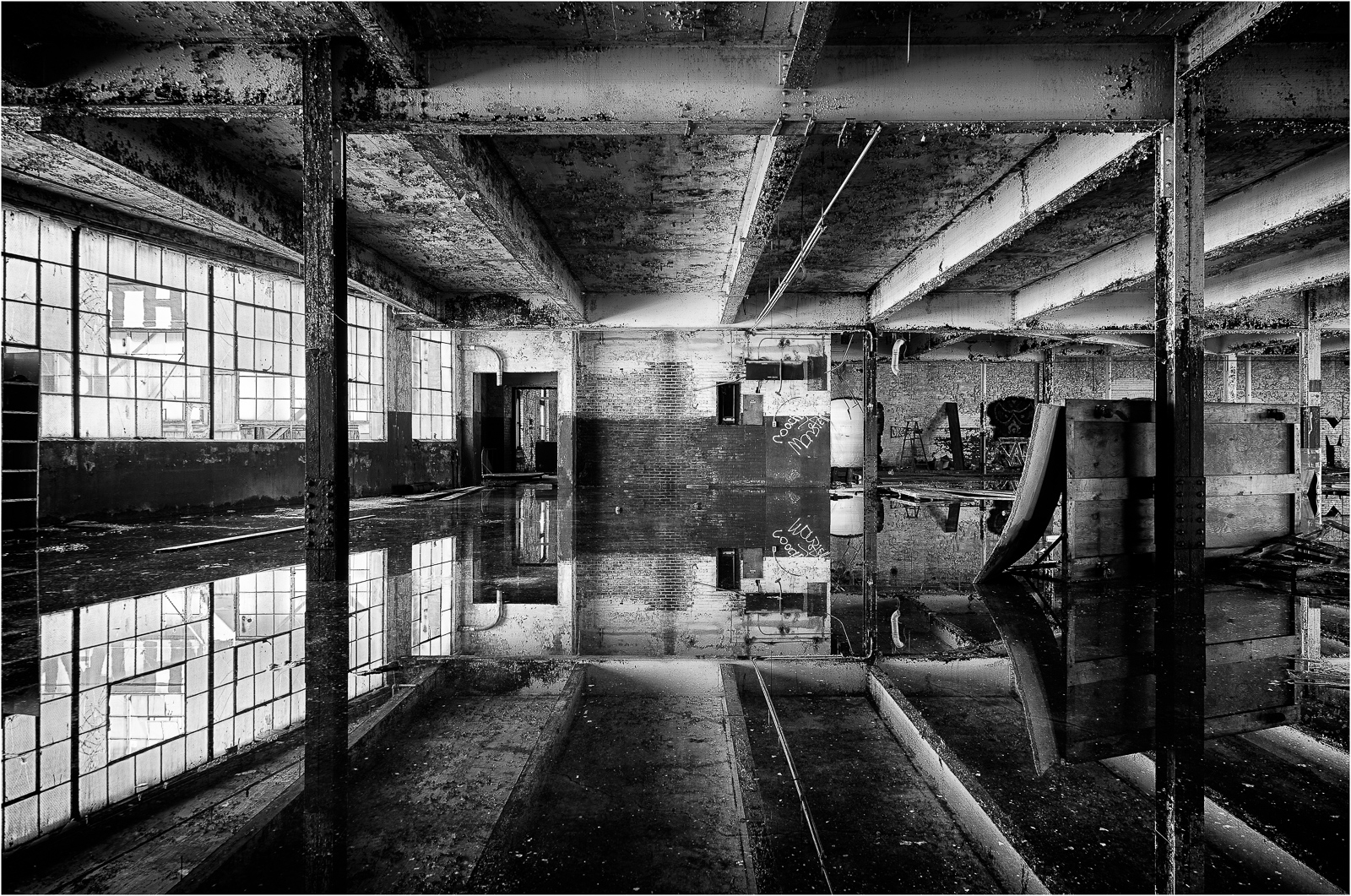 Abandoned interior space with reflective surfaces and industrial architecture.