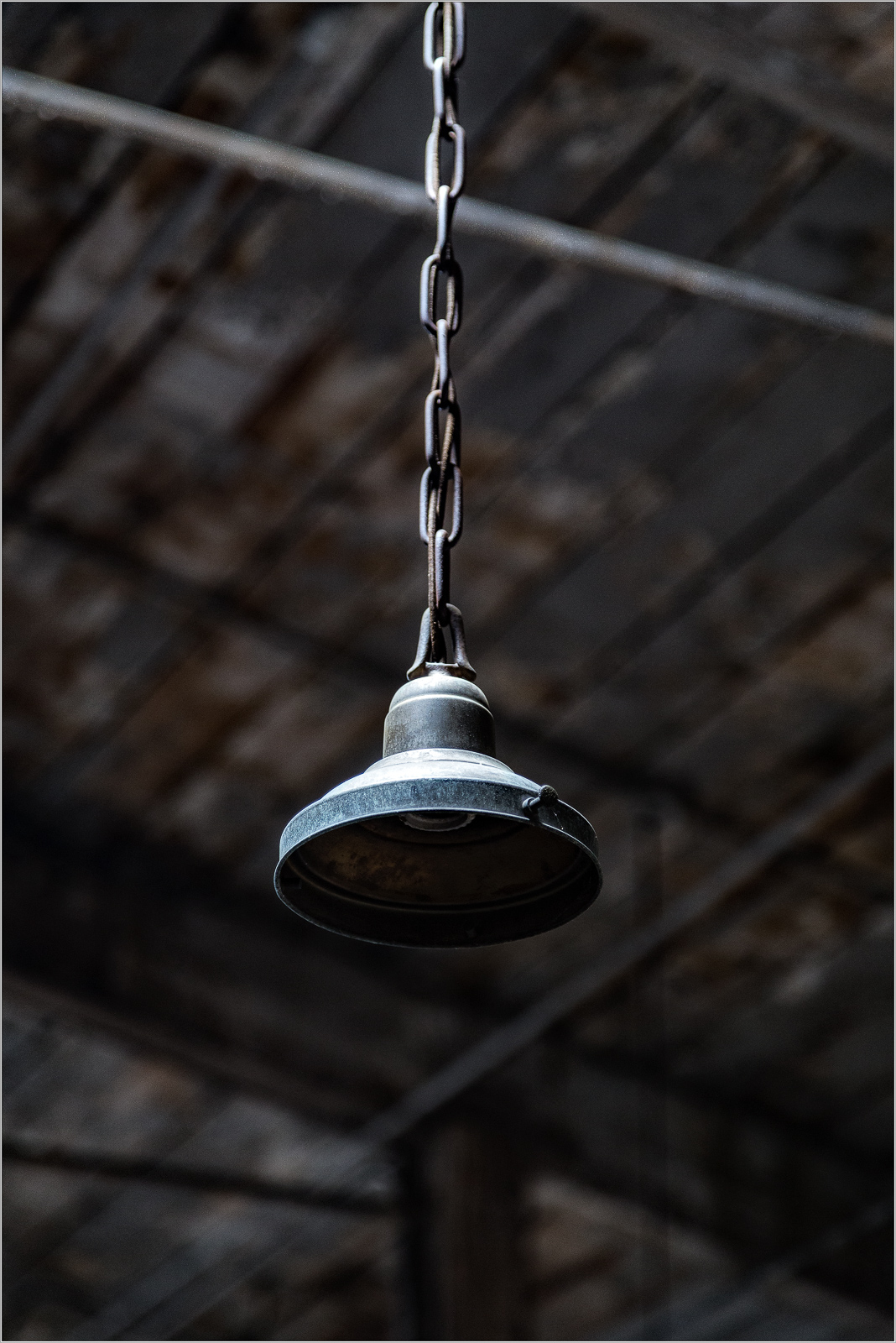 Hanging industrial light fixture with chain support in a rustic interior