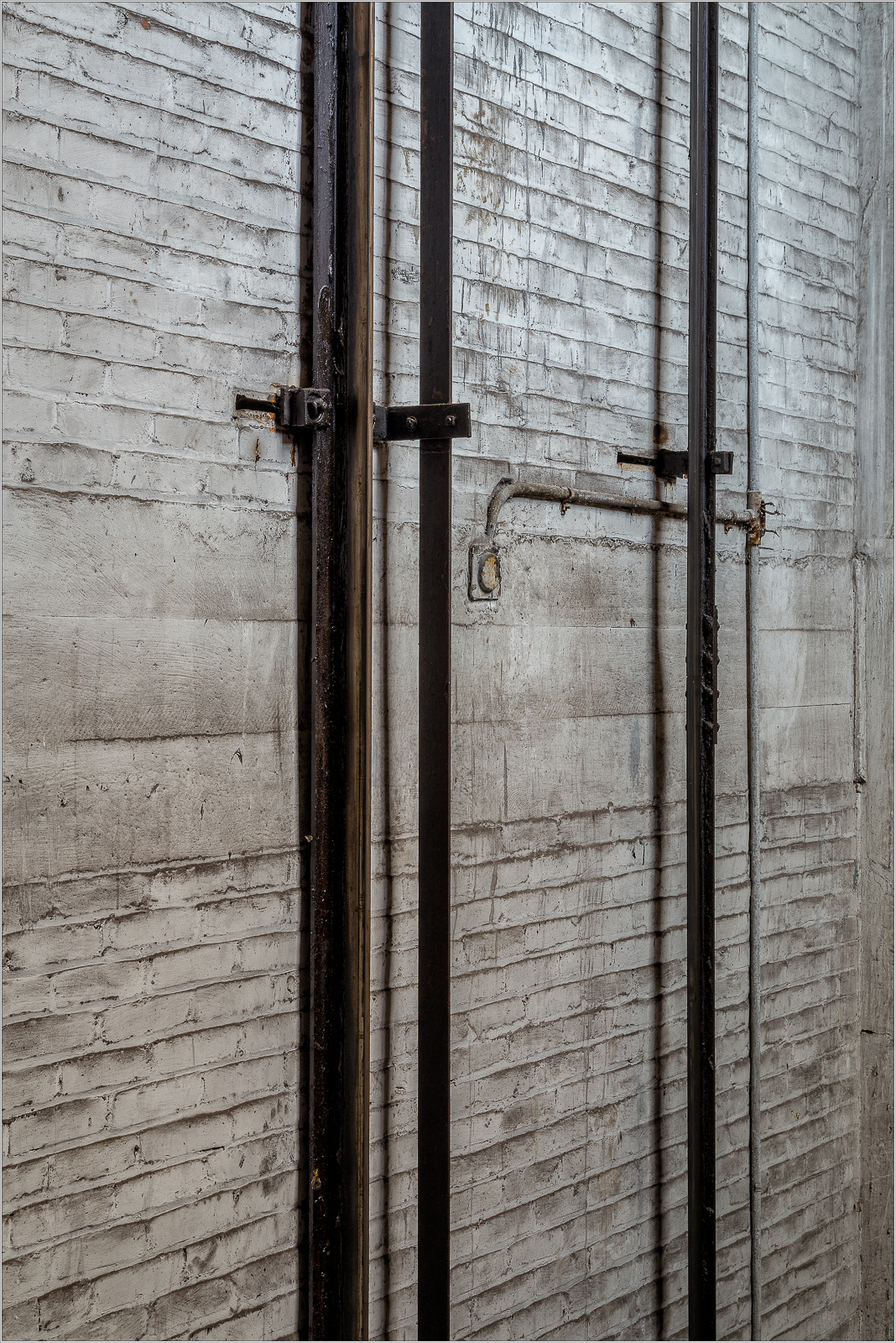 Industrial vertical pipes against textured concrete wall, showcasing urban decay and architecture.
