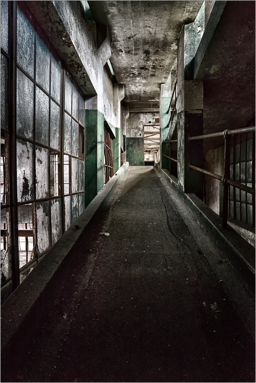Abandoned corridor with worn walls, faint light filtering through dusty windows.