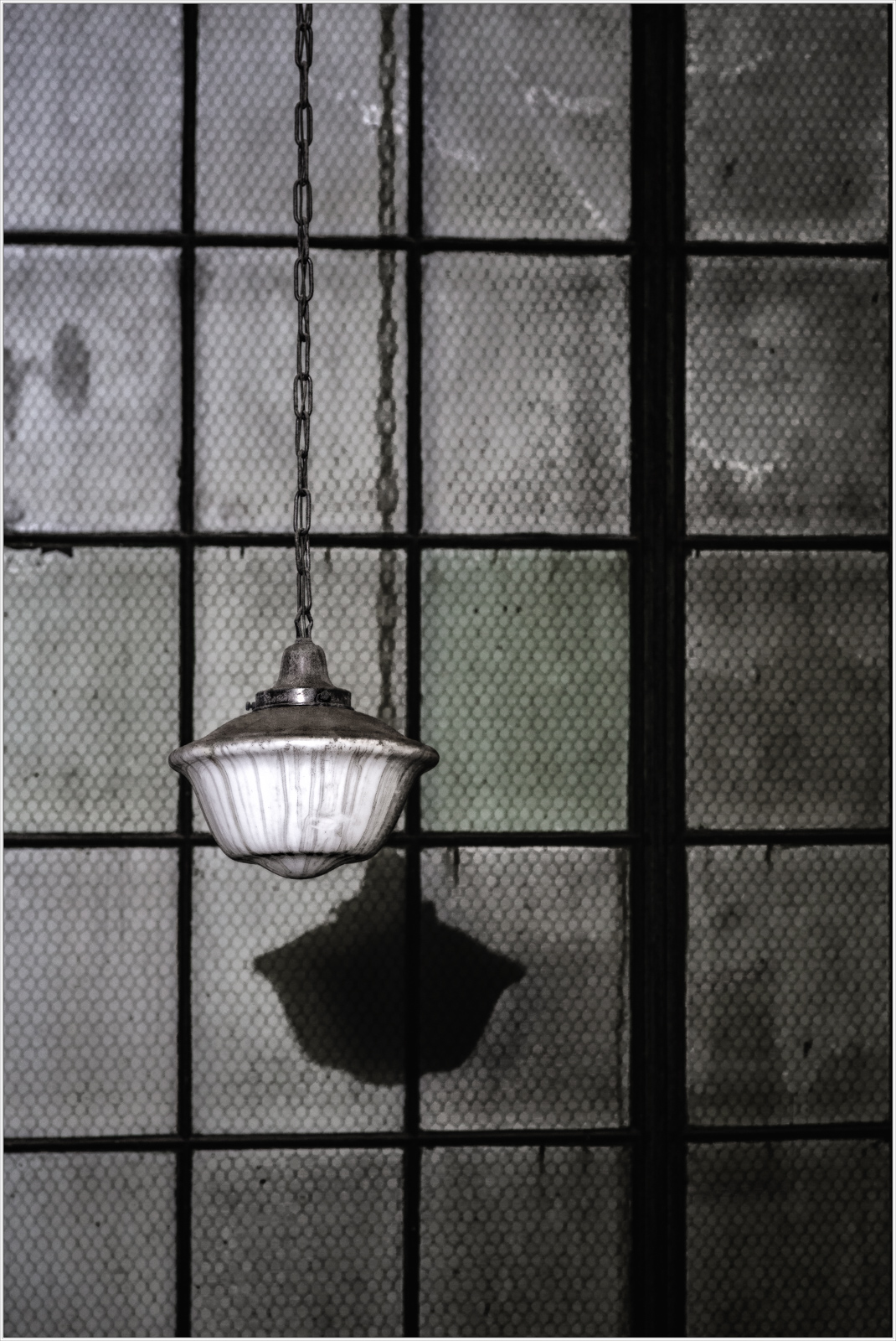 Hanging light shines bright, casting shadows on the wall, vintage glow in dark.