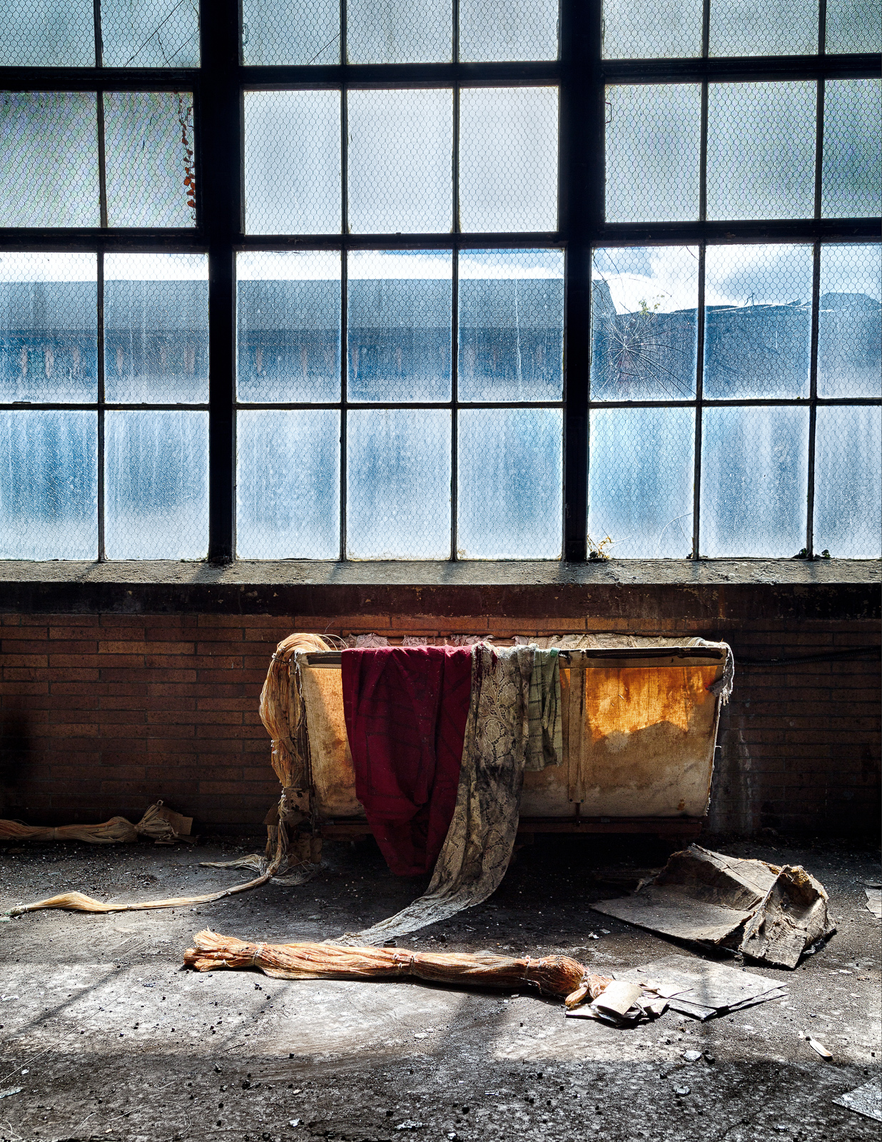 A forgotten tableau of decay with a draped fabric and dim light streaming through dusty panes.