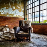 An abandoned chair, shrouded in time, amidst decaying walls and remnants of forgotten stories.