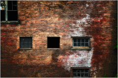 A weathered brick facade reveals time's silent touch and forgotten stories.