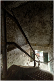 A dimly lit staircase with worn steps and peeling walls, shadows dance softly.