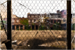 A cracked, webbed pane frames a desolate courtyard, whispers of time linger.
