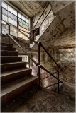 Weathered stairs ascend through quiet decay, where silence clings to stone walls.