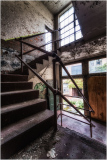 Rusty staircase in a worn, abandoned building; peeling walls whisper stories.