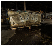 A rusted cart in a dilapidated industrial space, forgotten and still.