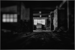 A dimly lit interior of the Scranton Lace Building with scattered debris and a window view.