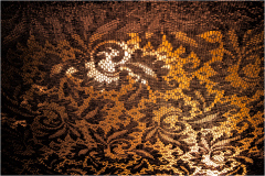 Intricate lace pattern with deep shadows and warm tones, revealing craftsmanship