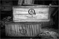 Wooden crates marked with a logo, stacked in an abandoned space.