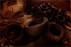 A haunting collection of aged, deflated tires amidst the shadows of neglect.