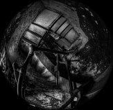 Dark staircase with peeling walls, shadowy corners, and a rusty railing.